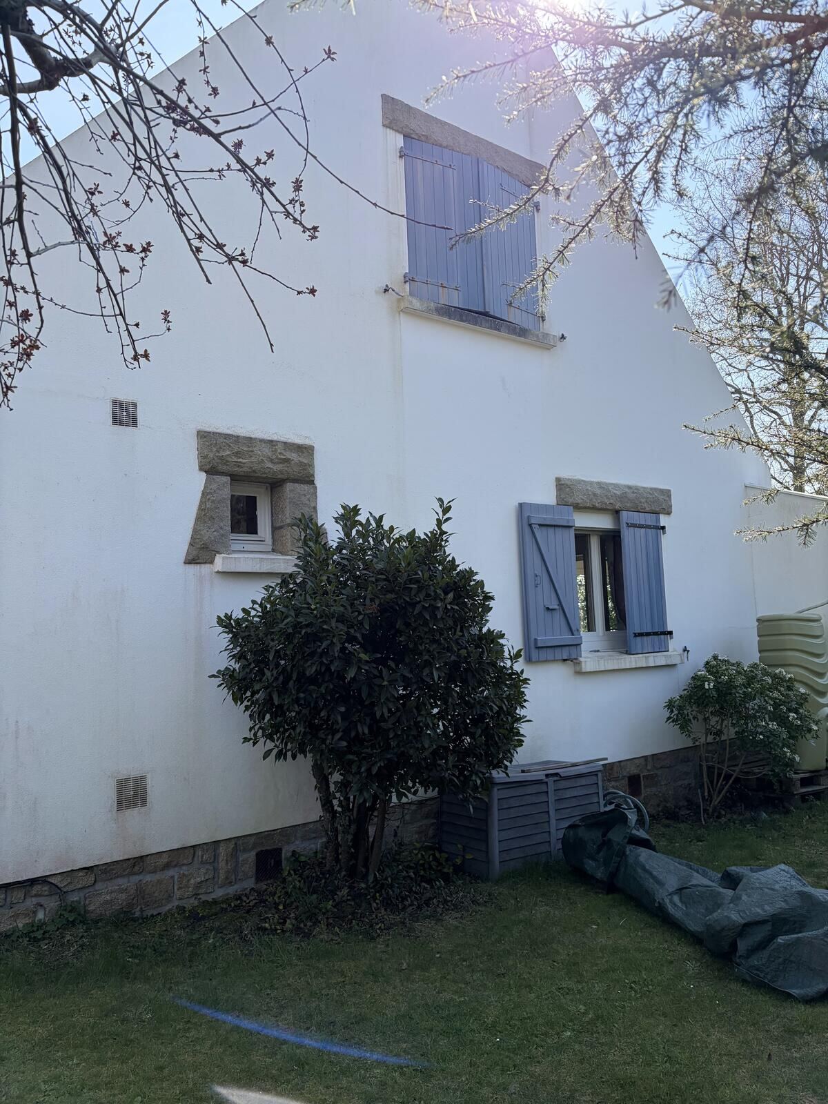 Façade nettoyée d'une maison bretonne aux volets bleus, encadrements en granit